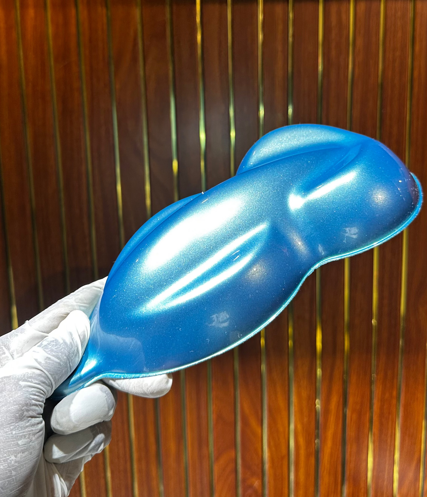 Blue balloon held by a gloved hand against a wooden panel background