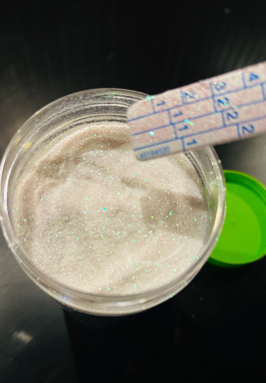 Glass container with white powder and a measuring spoon on a dark background